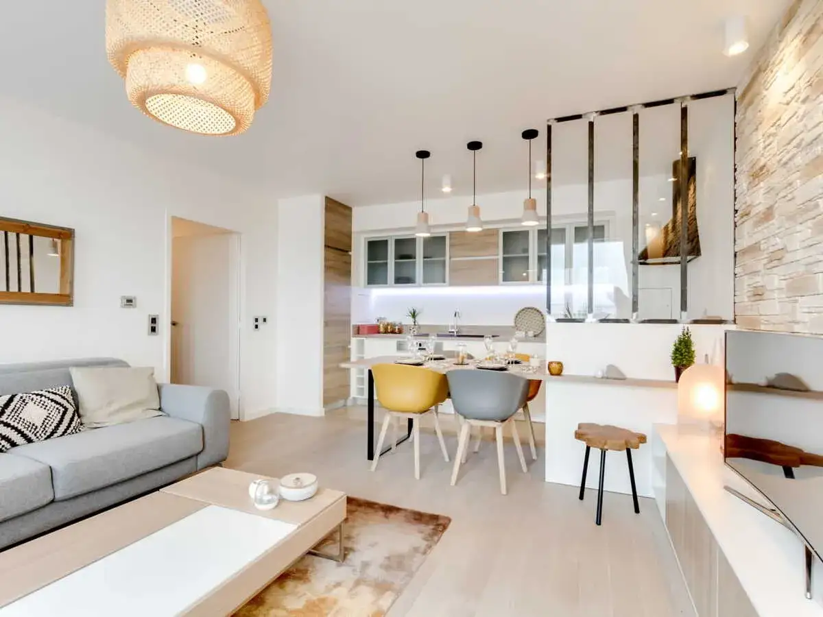 Aménagement intérieur appartement moderne : salon gris, cuisine épurée, table à manger design. Lumière chaleureuse.