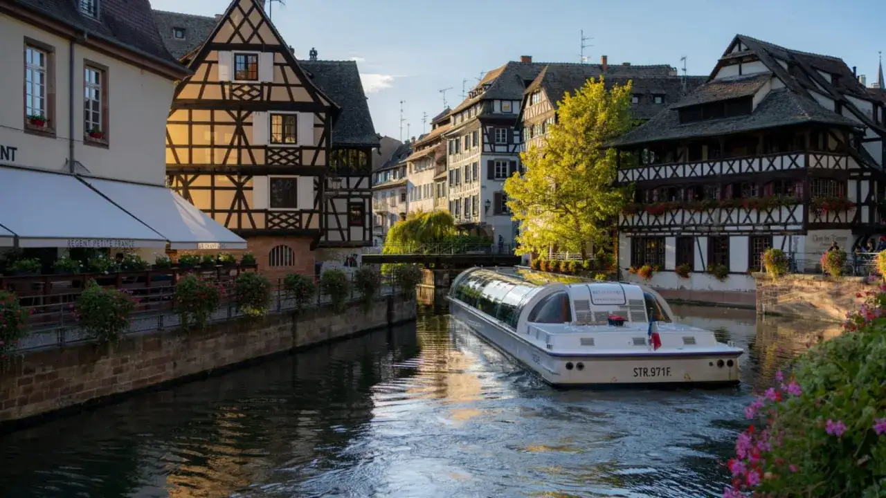 Bateau naviguant sur un canal à la Petite France à Strasbourg, entouré de maisons à colombages pittoresques.