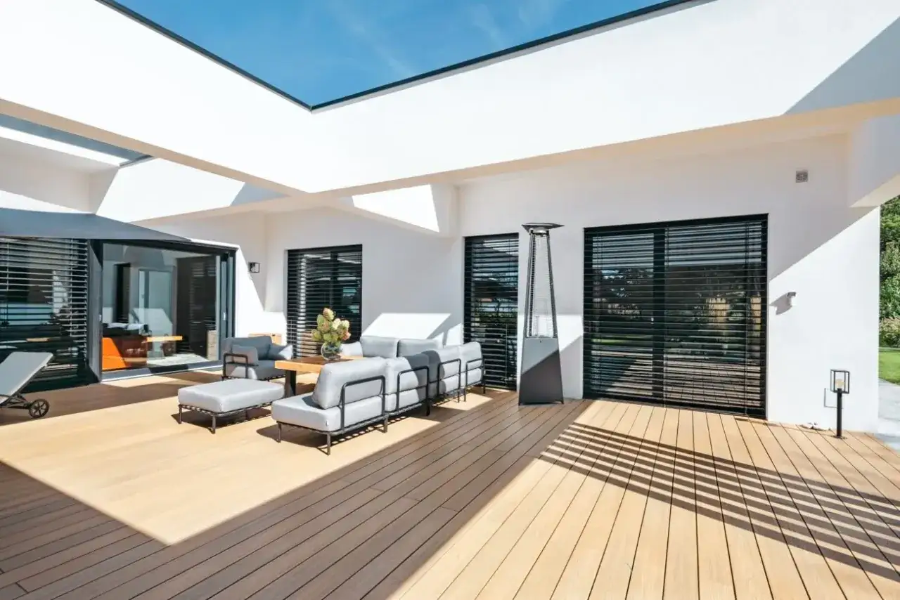 Am&eacute;nagement d'une terrasse ext&eacute;rieure moderne avec salon gris, table basse en bois et parasol chauffant.