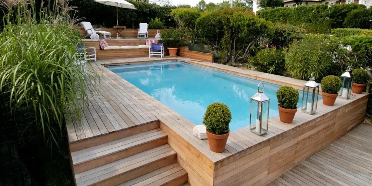 Magnifique habillage piscine semi enterrée en bois, avec terrasse, escaliers et végétation luxuriante.