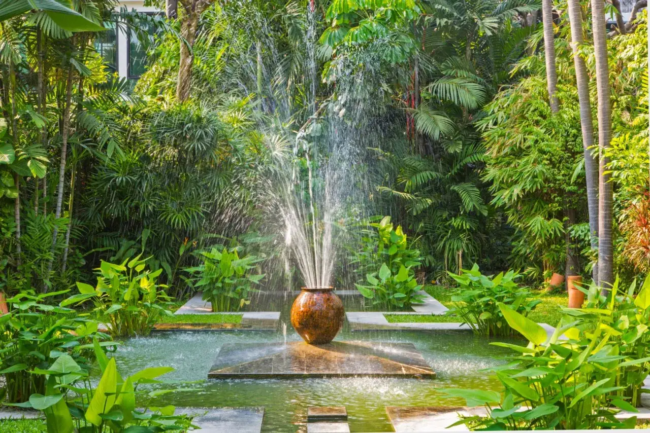 Fontaine d'eau jaillissant d'un pot en terre cuite, au cœur d'un jardin luxuriant. Une original deco jardin recuperation qui invite à la sérénité.