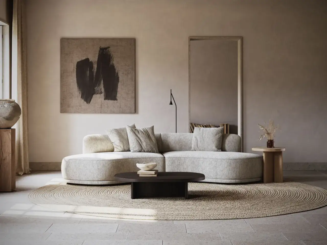 Un salon beige et blanc épuré avec un canapé arrondi, un tapis rond en jonc et une œuvre d'art abstraite.