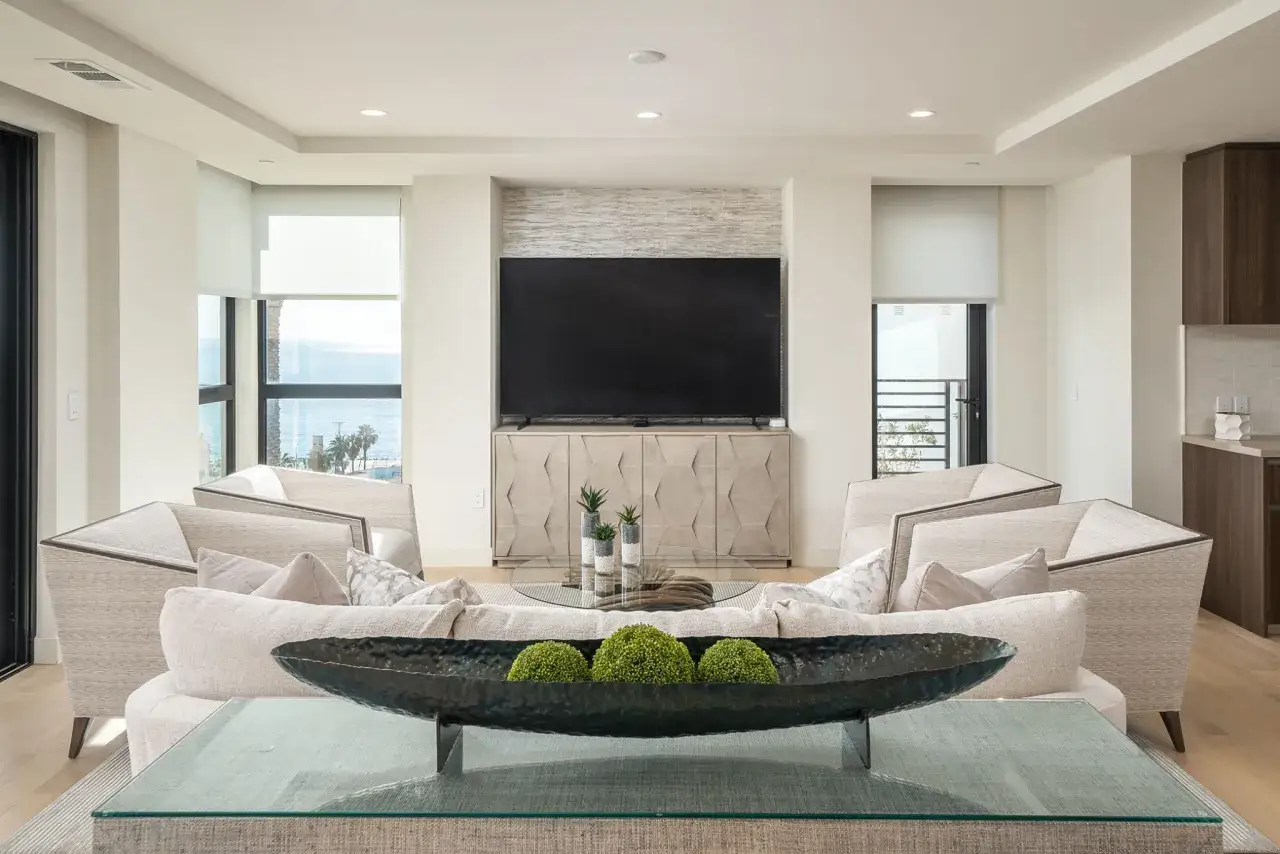 Salon moderne avec une cheminée murale TV, des fauteuils confortables et une décoration végétale.