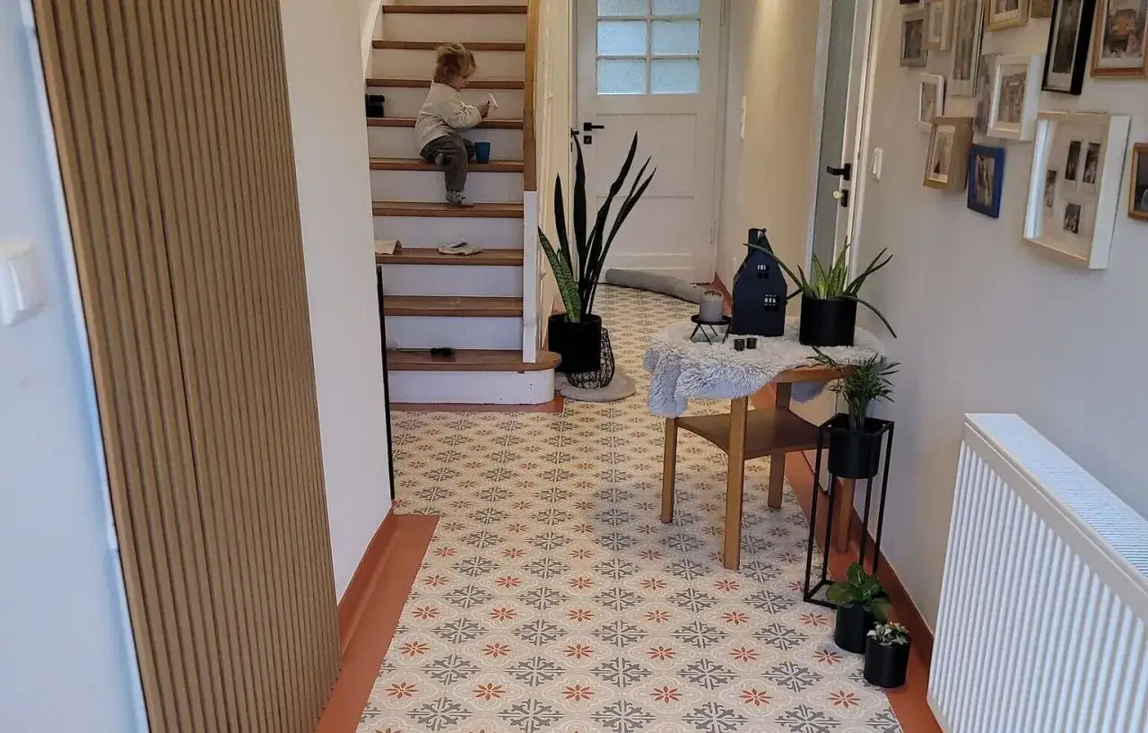 Un enfant sur les escaliers, un hall d'entrée décoré avec un carrelage au sol aux motifs floraux. L'idée de peindre carrelage sol pour un nouveau look.
