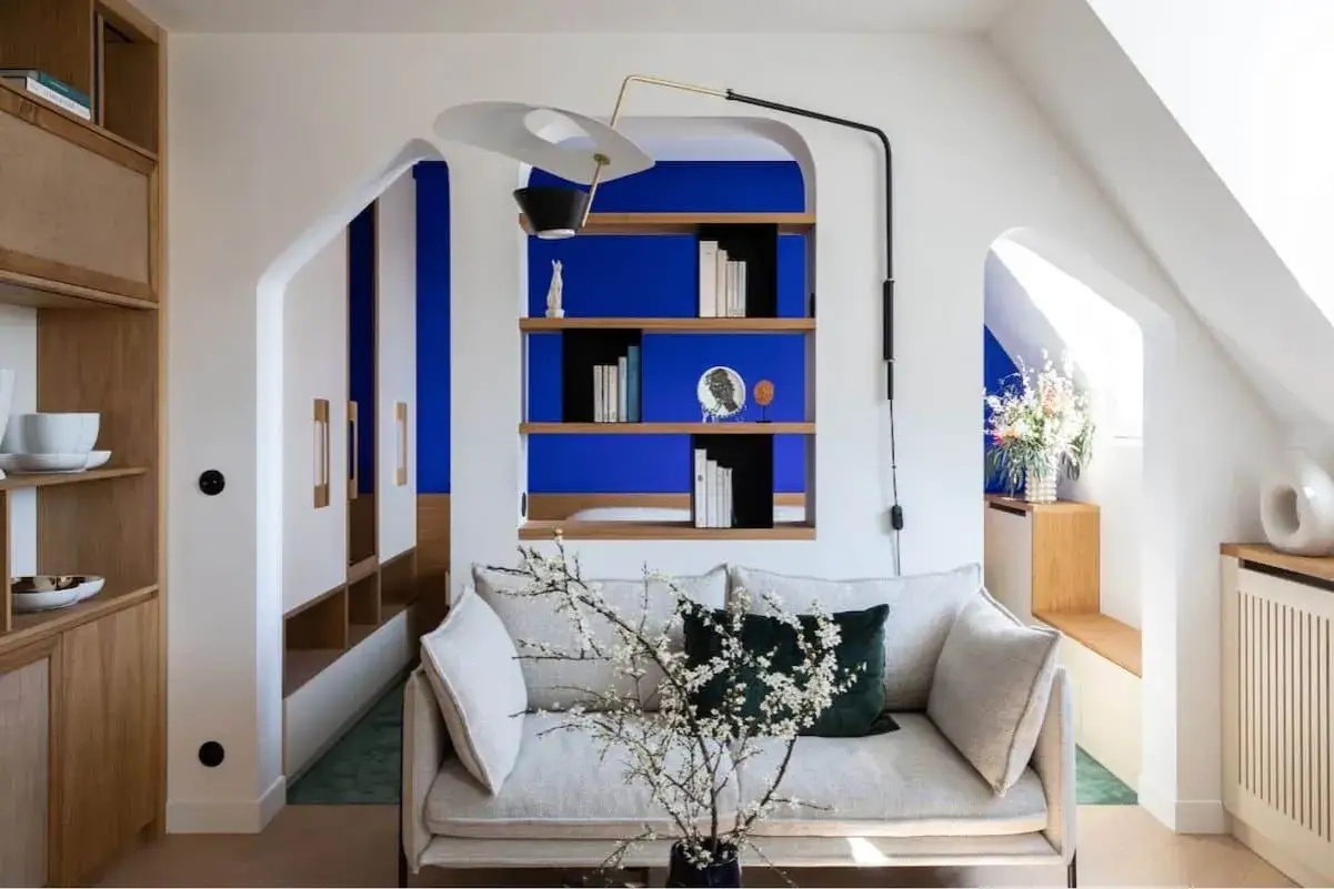 Salon moderne avec canap&eacute; clair, &eacute;tag&egrave;res bleues rappelant le bleu Klein et le bleu Majorelle, et des touches de bois naturel.