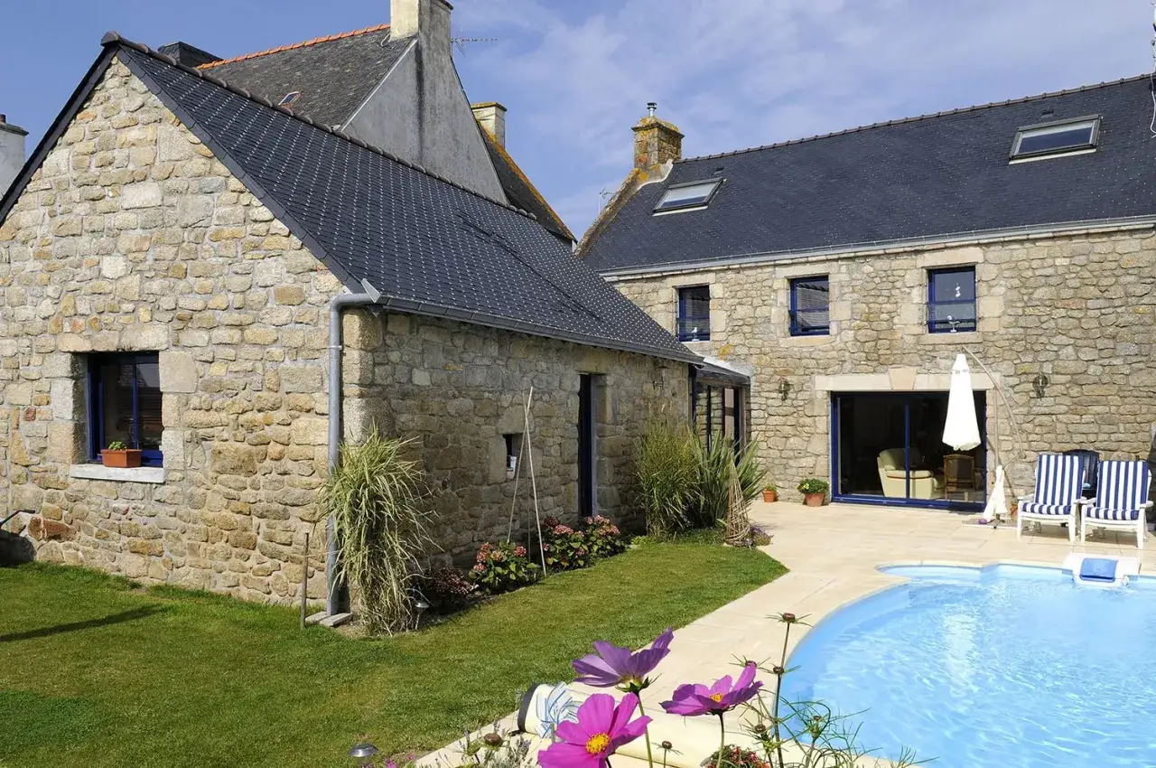 Maison ancienne en pierre, rénovation réussie avec piscine et jardin fleuri.