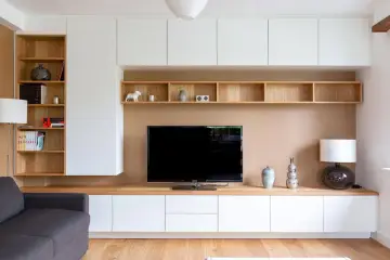 Un coin TV optimisé pour un petit espace, avec des étagères en bois et des rangements blancs.