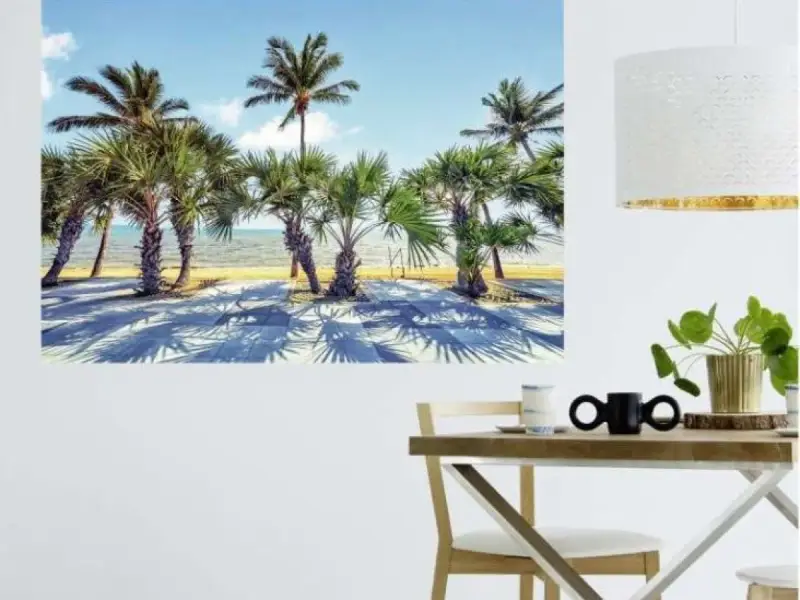 Une **déco murale originale** de palmiers sur une plage ensoleillée, projetant de longues ombres sur le sol.
