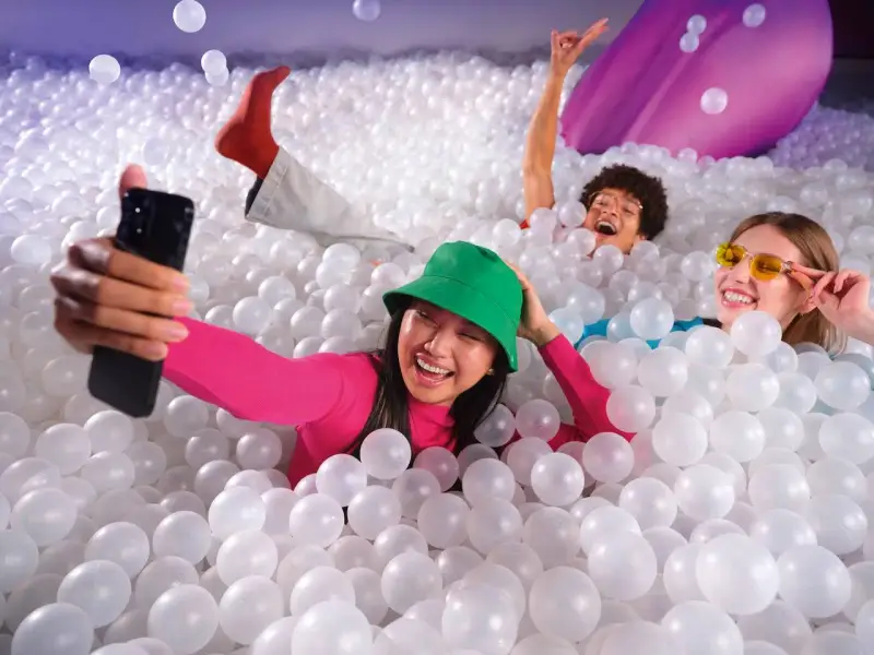 Trois amis s'amusent dans une piscine à balles, une expérience digne d'une **bubble planet Paris**.